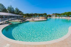 een groot zwembad met blauwe parasols in een resort bij Camping Le Palme in Marina di Bibbona
