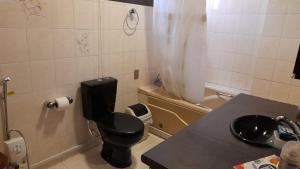 baño con aseo negro y lavamanos en El rincon de los Abuelos en Cochabamba