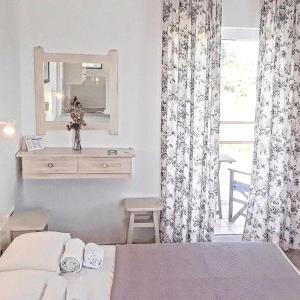 a bedroom with a bed and a dresser and a mirror at Voula Accommodation in Agios Georgios