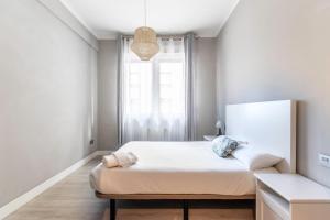 ein weißes Schlafzimmer mit einem Bett und einem Fenster in der Unterkunft Piso reformado en Bilbao centro in Bilbao