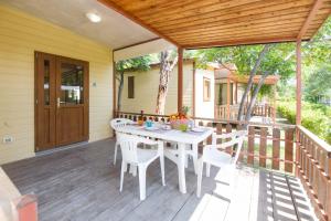 Camping Le Palme في مارينا دي بيبونا: طاولة بيضاء وكراسي على سطح خشبي