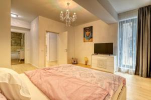 een slaapkamer met een groot bed en een televisie bij Luxurious 2 Bedroom Apartment in Herastrau in Boekarest