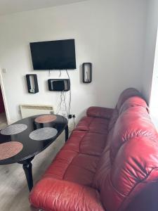 a living room with a red couch and a table at Lovely 2 bedroom Flat at Palm Court in Bournemouth,5 minutes away from beach, whole flat is yours for the time you stayed in Bournemouth
