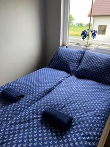 1 cama con edredón azul y ventana en Domki u Anety, en Górkło