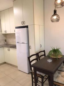 a kitchen with a table and a white refrigerator at Daissy house - דירה פרטית בנאות גולף in Caesarea