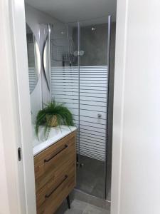 a bathroom with a shower and a wooden vanity with a sink at Daissy house - דירה פרטית בנאות גולף in Caesarea