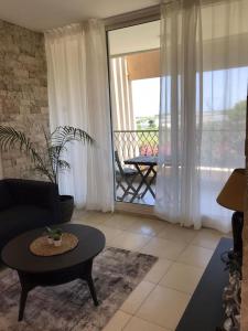 a living room with a coffee table and a balcony at Daissy house - דירה פרטית בנאות גולף in Caesarea