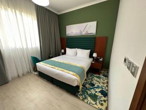 a bedroom with a bed in a green room at BANIYAS PLAZA HOTEL APARTMENTS in Abu Dhabi