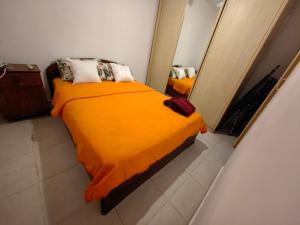 een slaapkamer met een bed met een oranje deken en een spiegel bij near the sea even 14 days won't feel enough in Bat Yam