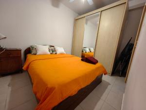 een slaapkamer met een bed met een oranje deken bij near the sea even 14 days won't feel enough in Bat Yam