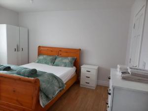 um quarto com uma cama de madeira e uma cómoda branca em Buncrana Class 5 double bed em Buncrana