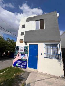 Biały dom z niebieskimi drzwiami na ulicy w obiekcie CASA Privada Wifi CLIMAParking Netflix REFRI Micro w mieście Monterrey