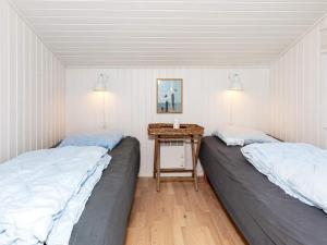two beds in a room with a small table at Four-Bedroom Holiday home in Fjerritslev 3 in Torup Strand
