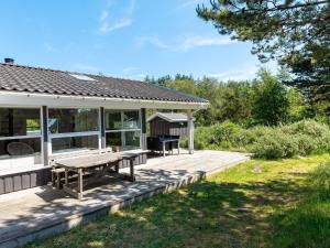 a house with a picnic table on a deck at Four-Bedroom Holiday home in Fjerritslev 3 in Torup Strand