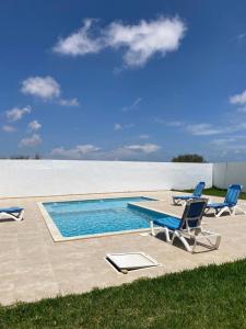 two lounge chairs and a swimming pool in the sand at Maison de Noé Djerba Midoun in Midoun