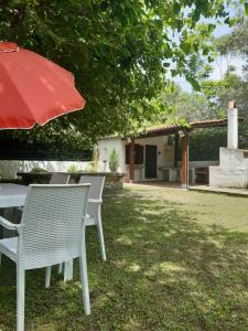 - une table et des chaises avec un parasol rouge dans la cour dans l'établissement Villa Livia, à Villammare