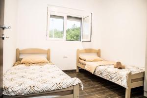 2 Betten in einem Zimmer mit 2 Fenstern in der Unterkunft Village house Katarina in Cetinje