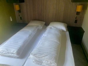 a room with three beds with white sheets and pillows at Wellnesslodge Specht in Dalerveen
