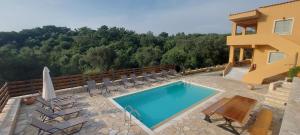 a swimming pool with chairs and a house at Villa Kostas-NE Corfu with heated salt swimming pool in Agios Spyridon Corfu