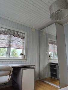 Habitación con escritorio con silla y 2 ventanas. en Cozy family house, en Tromsø