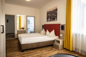 Schlafzimmer mit einem großen Bett und gelben Vorhängen in der Unterkunft Hotel Grüner Baum in Bühlertal