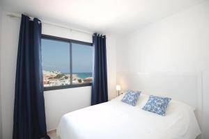 una camera con un letto bianco e una grande finestra di Apartamento Domínguez, Fuerteventura a Morro del Jable