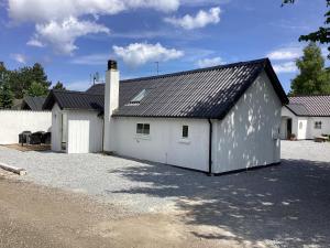 une grange blanche avec un toit noir dans l'établissement Feriehus - Marielyst centrum, à Bøtø By