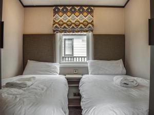 2 camas en un dormitorio con ventana en Holywell Sunset, en Cubert