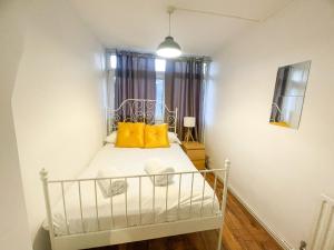 a small bedroom with a bed with yellow pillows at Flat 4, Kingsbury house in London