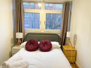 two red pillows on a white bed with a window at Flat 4, Kingsbury house in London