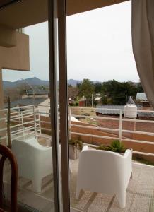 a balcony with white chairs and a view of a building at Hermoso Triplex en Sierra de la Ventana in Sierra de la Ventana