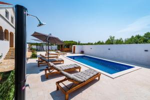 a swimming pool with two lounge chairs and an umbrella at Villa Gabi in Pridraga