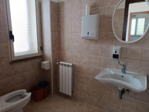 a bathroom with a sink and a toilet and a mirror at Agriturismo Sant'Anna Ortì in oliveta biologica con vista sullo Stretto di Messina in Orti