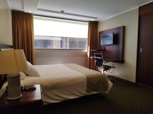 a hotel room with a bed and a chair and a window at Suite Akros in Quito