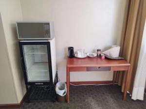 a room with a desk with a microwave and a television at Suite Akros in Quito