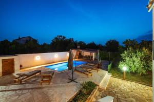 a swimming pool in a backyard at night at Villa Gabi in Pridraga