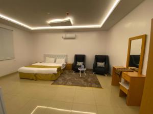 a bedroom with a bed and two chairs and a mirror at Lona Park in Taif