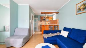 a living room with a blue couch and a chair at Teleexpresu Apartamenty PIAMOLA in Krynica Morska