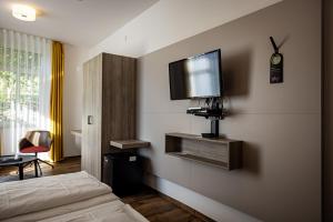 ein Schlafzimmer mit einem Bett und einem TV an der Wand in der Unterkunft Hotel Grüner Baum in Bühlertal