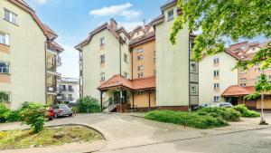 un edificio de apartamentos con coches aparcados en un aparcamiento en Teleexpresu Apartamenty PIAMOLA en Krynica Morska