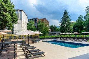 a pool with chairs and umbrellas next to a building at Emilia Lux Rooms in Vrnjačka Banja