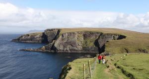 a group of people walking on a hill next to the ocean at Meadow Cottage in Belmullet +18 photos