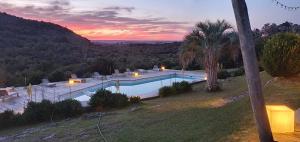a swimming pool with a sunset in the background at Villa Serrana - Mesón de las cañas in Villa Serrana