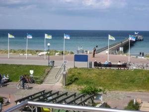 une plage avec des drapeaux et des personnes assises sur des bancs dans l'établissement Strandfewo am Schönberger Strand, à Schönberger Strand