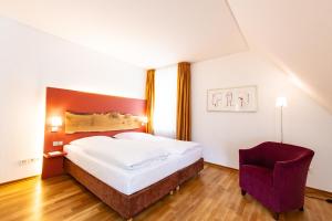 ein Hotelzimmer mit einem Bett und einem Stuhl in der Unterkunft Parkhotel Wolfsburg in Wolfsburg