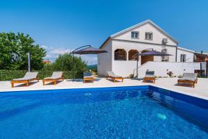 a pool in front of a house with chairs and umbrellas at Villa Gabi in Pridraga