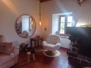 uma sala de estar com um sofá, uma cadeira e um espelho em 21lemonde em Le Brignon