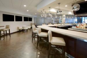 a bar in a restaurant with white chairs and a counter at Sheraton Miami Airport Hotel and Executive Meeting Center in Miami