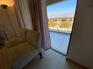 una silla en una habitación con vista a un balcón en Siena Sun Apartment 6 with water reserve, en Midrand