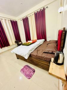 a bedroom with a large bed with purple curtains at Secrets of Parvati in Kalgha